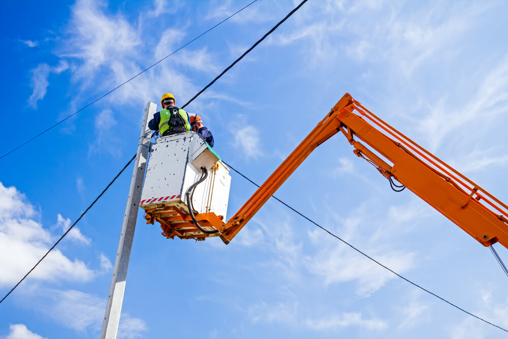 telecom truck with utility worker in bucket fixing power lines