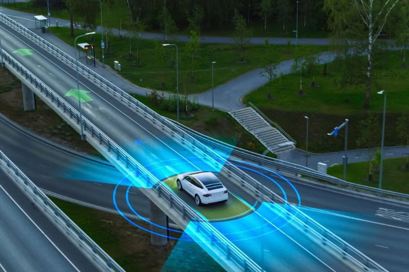 Autonomous vehicle drives down highway with sensors tracking road and surroundings for safety hazards.