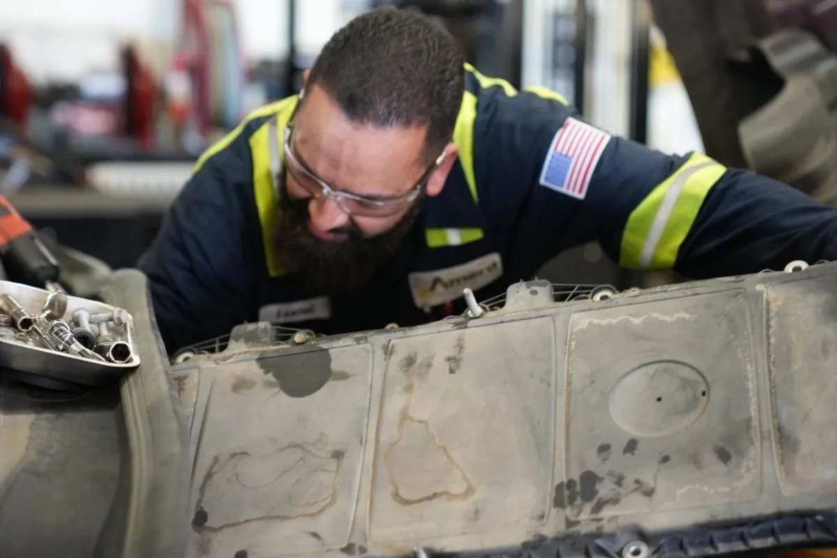 Technician repairing tanker truck engine.