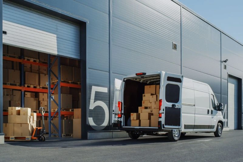 Last mile delivery van parked in front of distribution hub bay, and boxes are being packed into the vehicle.