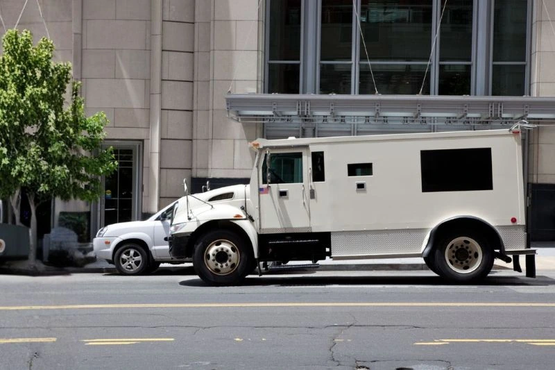 Armored transport driving down city street to deliver cash and secure goods for bank.