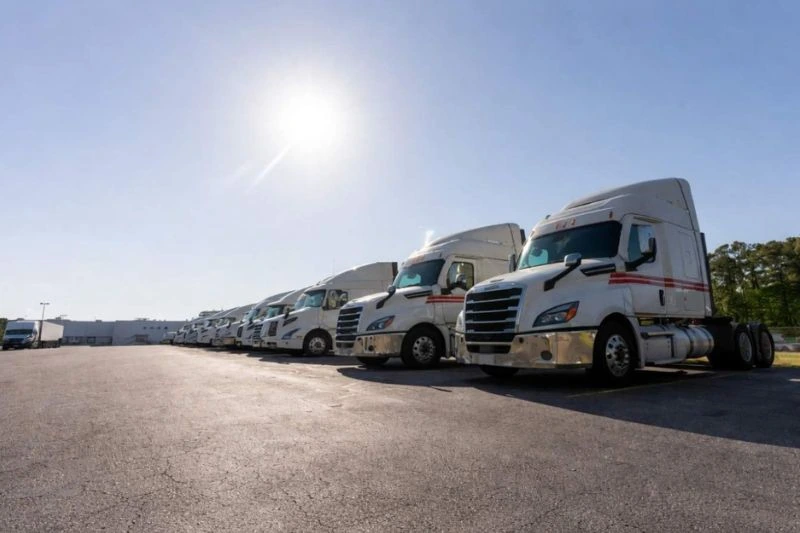Trucking fleet including tractors, parked at freight maintenance yard.