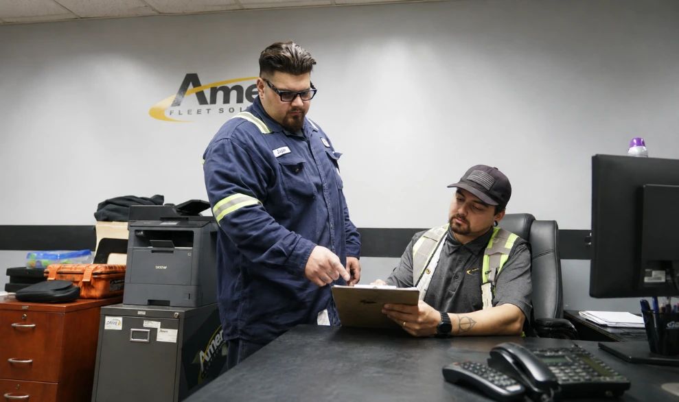 Two techs looking at a clipboard reviewing accident claims recovery