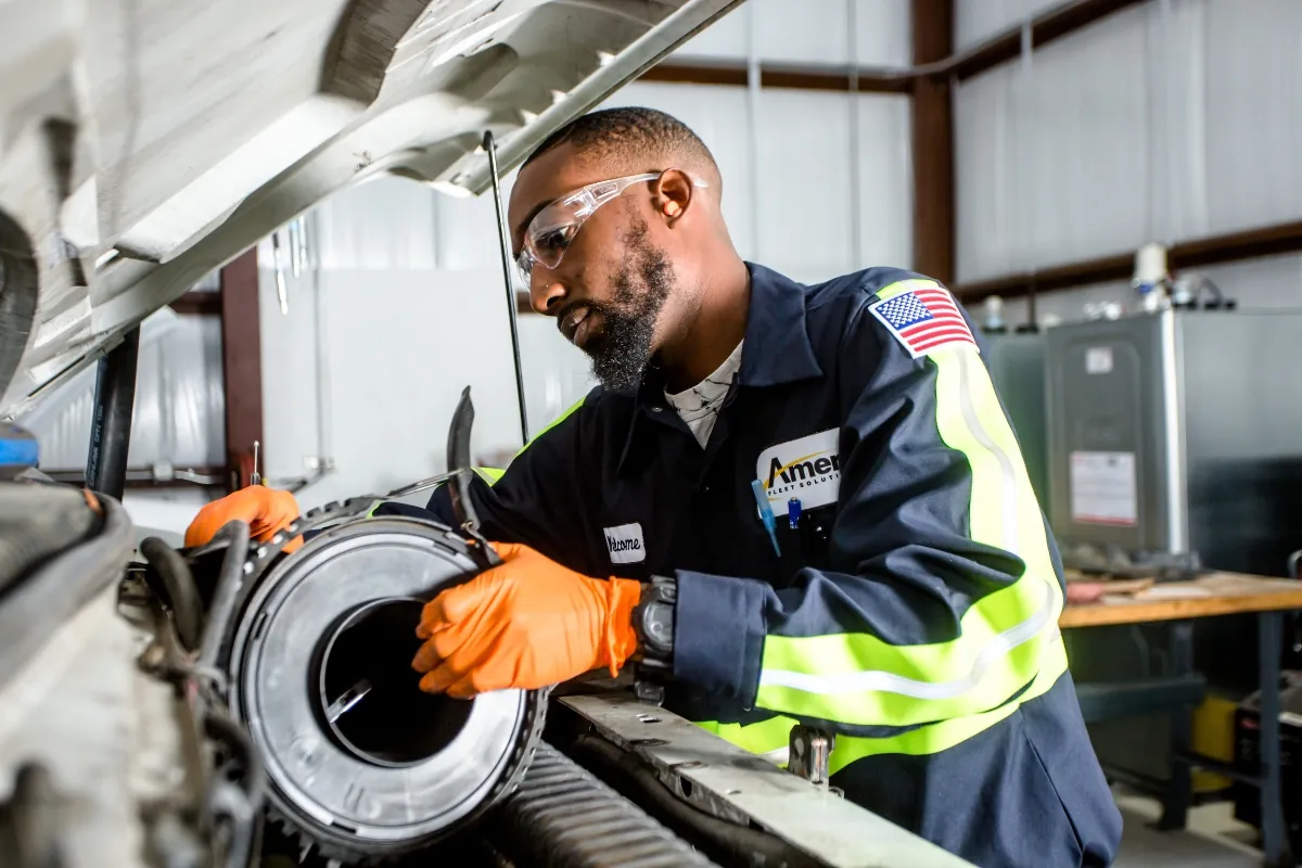 Amerit technician at fleet service center performing fan belt replacement and engine maintenance on customer's vehicle